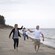 A couple swings their young son up in the air between them as they walk along the beach